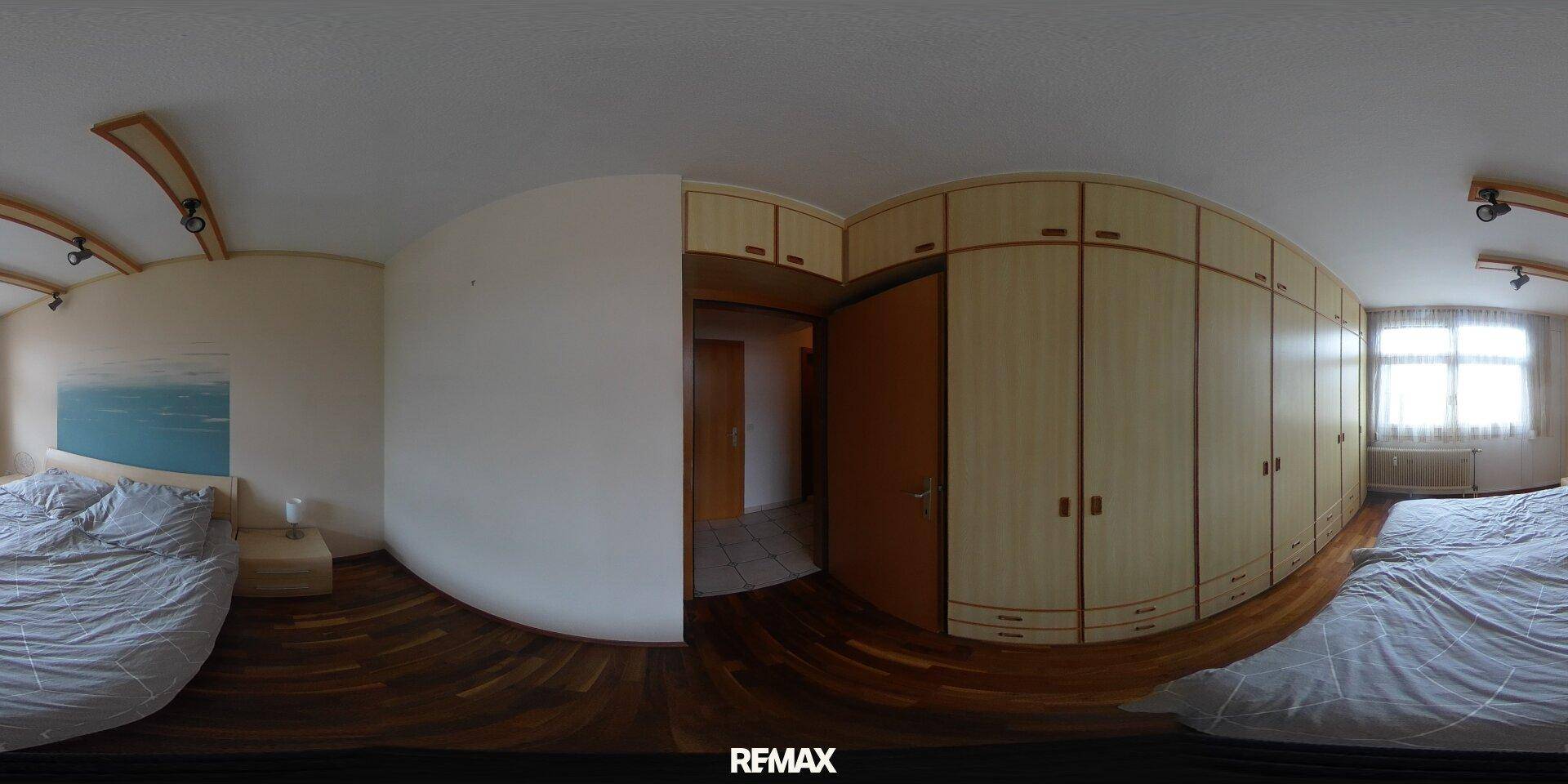 Panoramaansicht eines Schlafzimmers mit großem Bett, Holzschränken und viel Tageslicht.