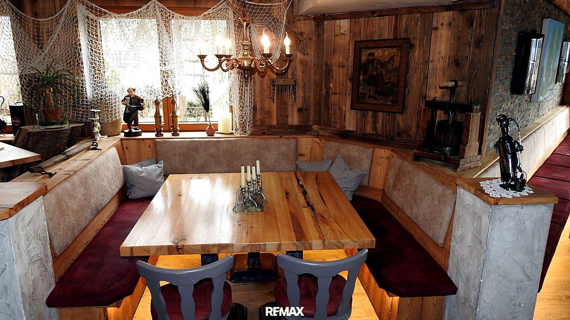 Rustikaler Essbereich mit großer Holztafel, Eckbank und traditioneller Beleuchtung.