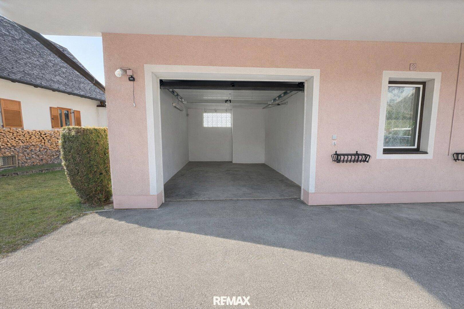 Leere Garage mit Betonboden und einem kleinen Fenster, bereit zur Nutzung.