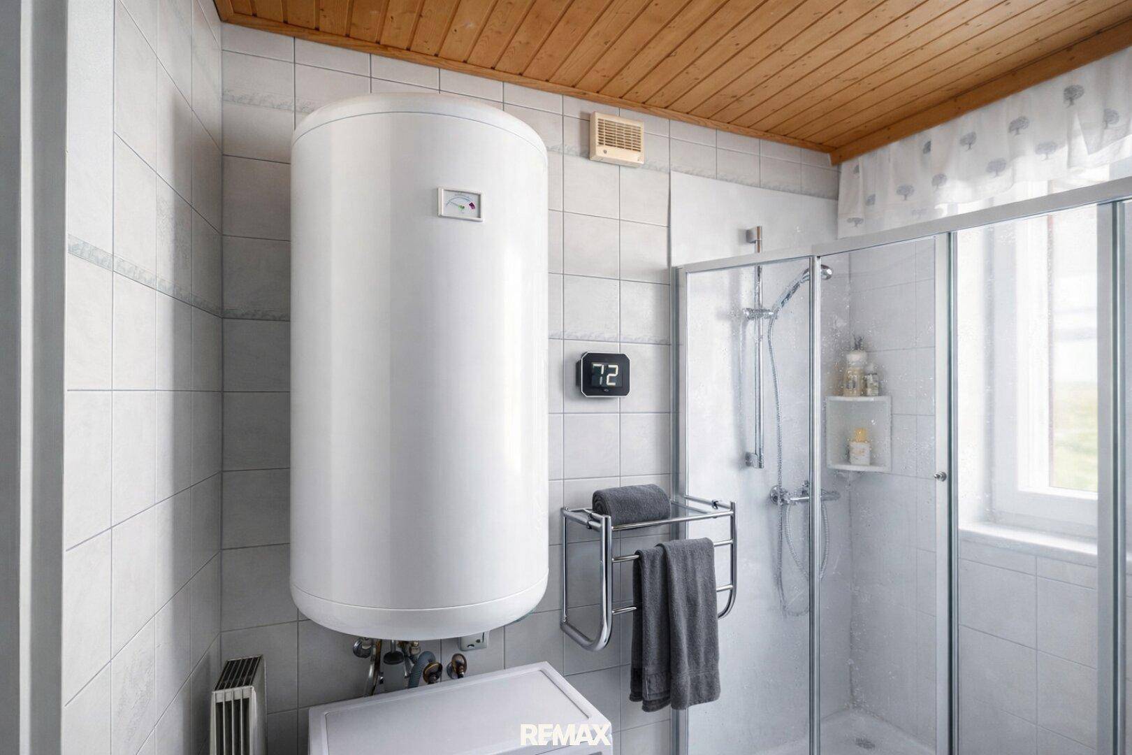 Badezimmer mit Dusche, Warmwasserboiler und Holzdecke, praktisch und sauber.