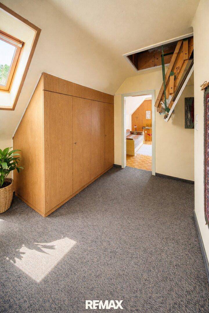 Dachbodenraum mit Teppichboden, Dachfenster und praktischen Einbauschränken.