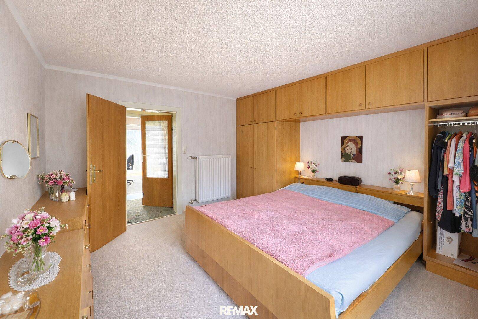 Geräumiges Schlafzimmer mit Doppelbett, Einbauschränken und Zugang zum Flur.