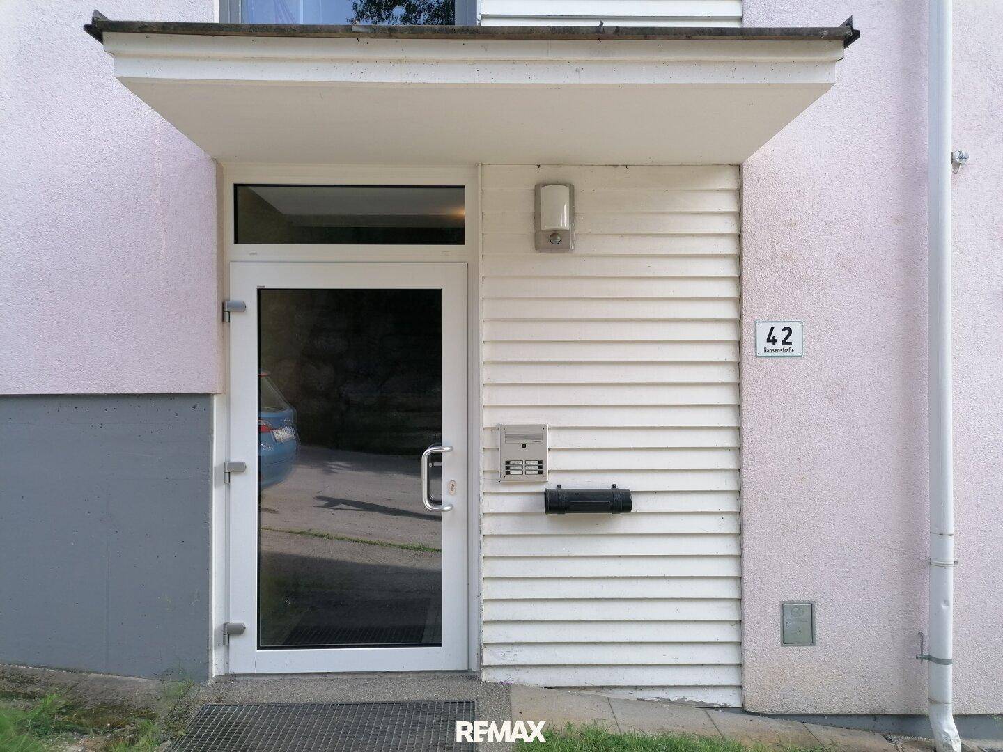 Haupteingang des Gebäudes mit einer modernen Glastür und der Hausnummer 42.