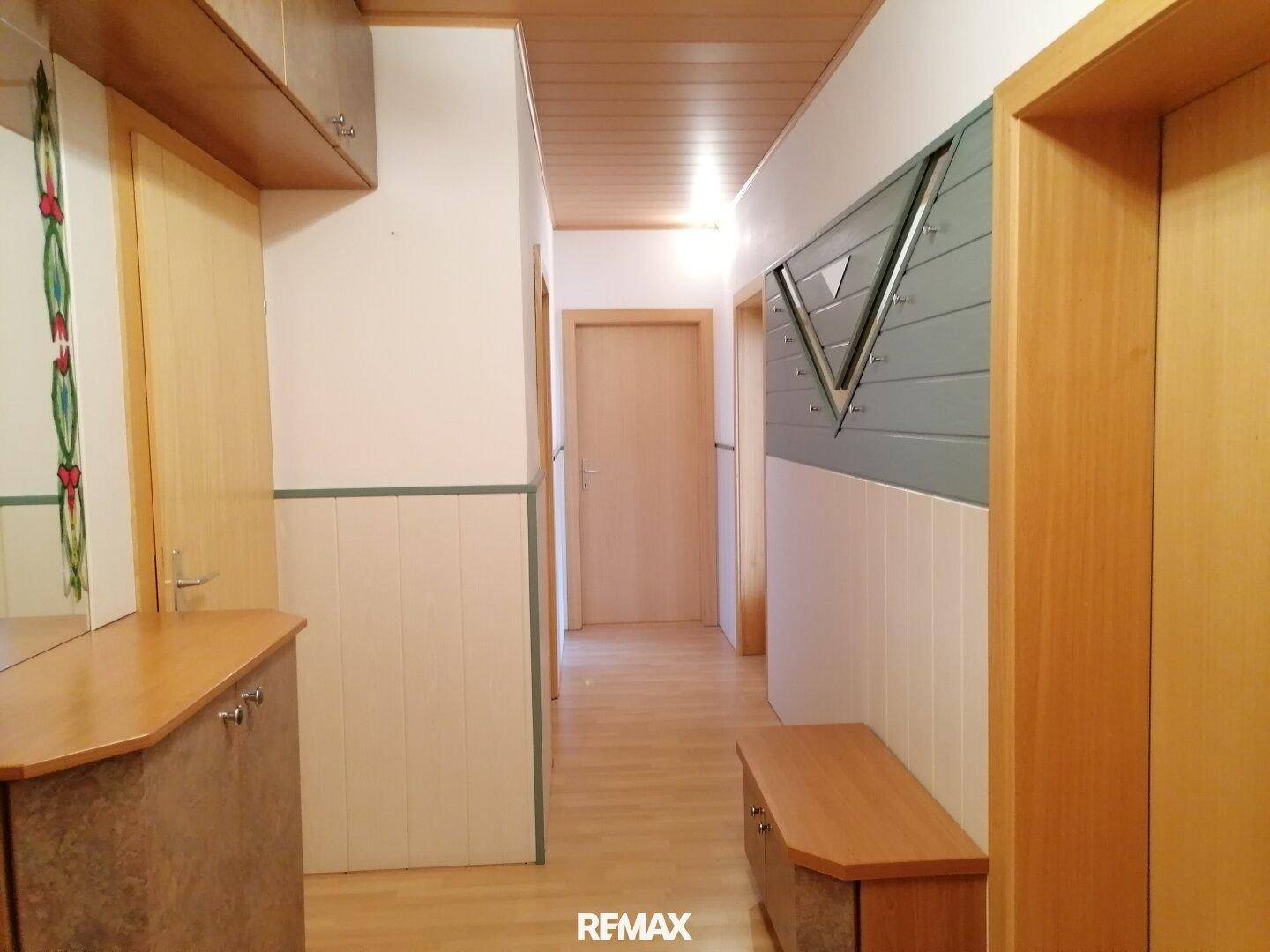 Heller Flur mit Holzdeckenverkleidung, Holzboden und mehreren Türen.