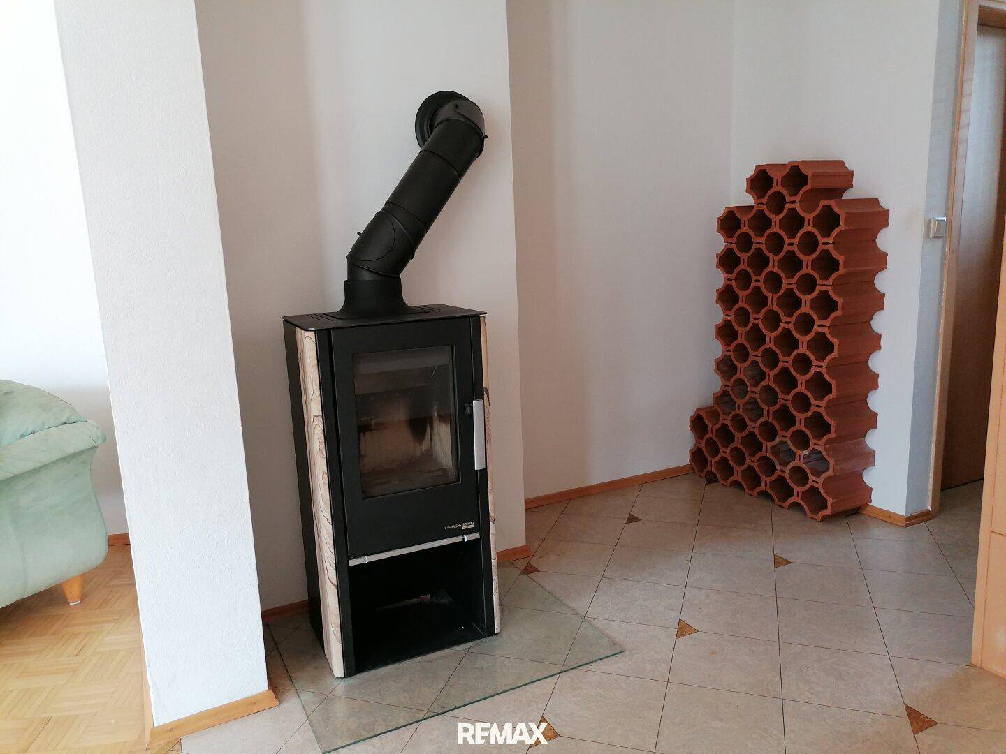 Gemütlicher Raum mit einem modernen Holzofen und einem dekorativen Weinregal.