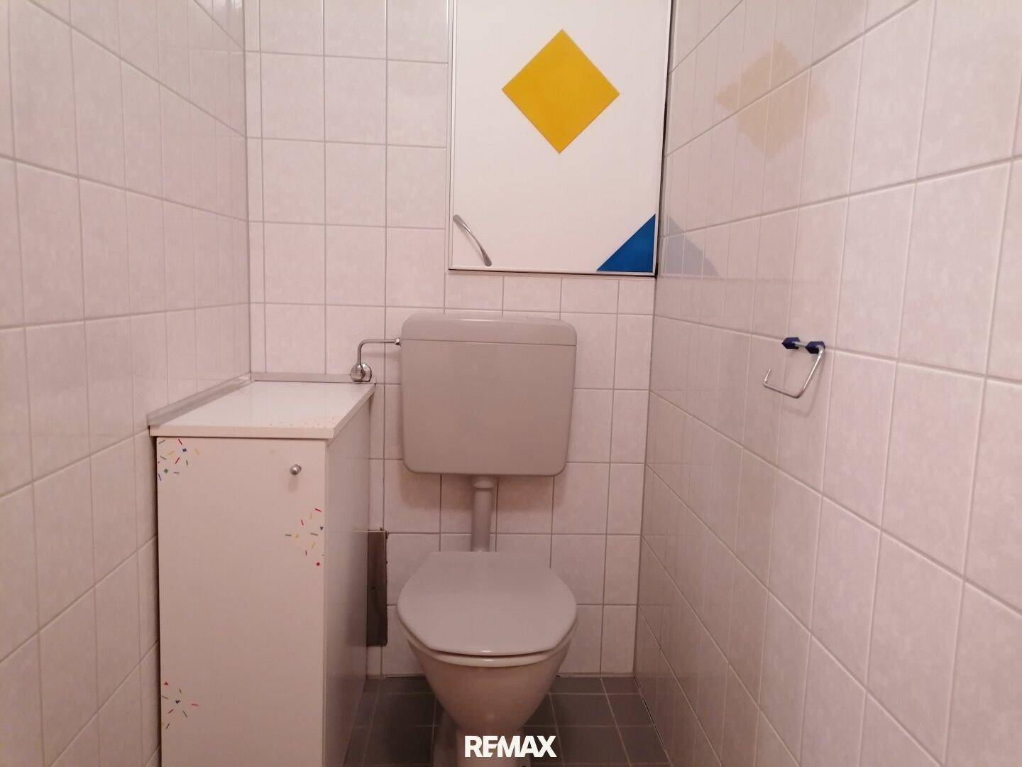Separates WC mit Toilette und hell gefliesten Wänden.