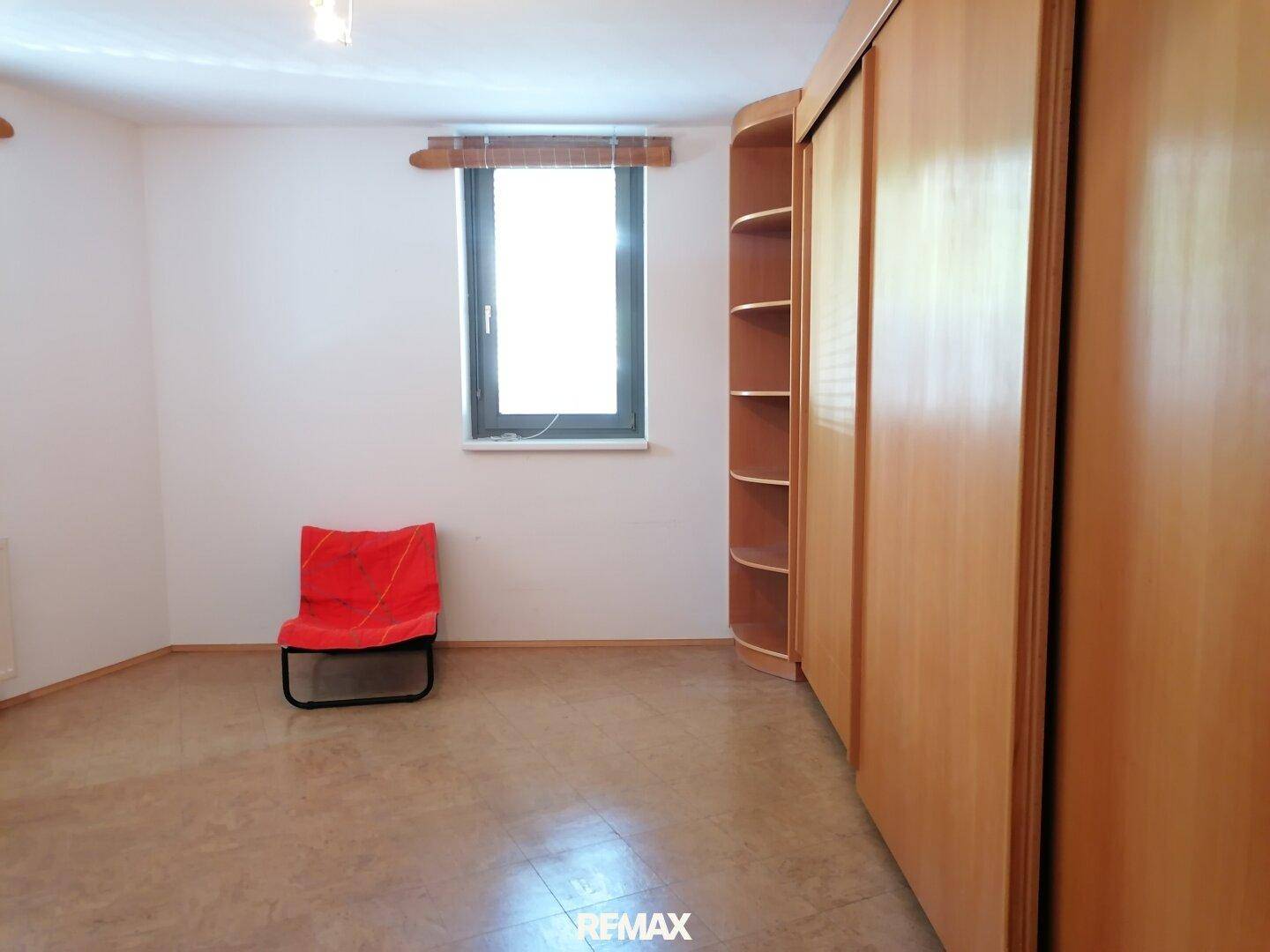 Schlafzimmer mit praktischen Einbauschränken aus Holz und Fliesenboden.