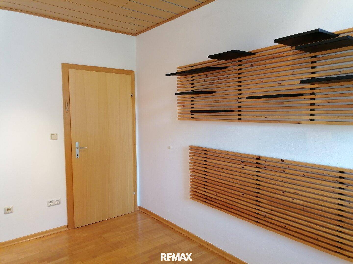 Zimmer mit Holzboden und dekorativen Holzpaneelen an der Wand.