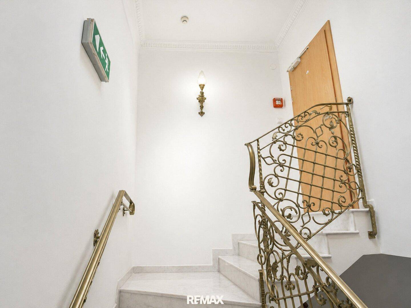 Treppenhaus mit Marmorstufen, schmiedeeisernem Geländer und Stuckdecke.