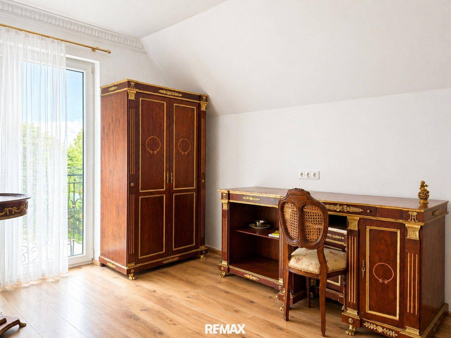 Schlafzimmer mit Holzboden, klassischem Mobiliar und Zugang zu einem französischen Balkon.