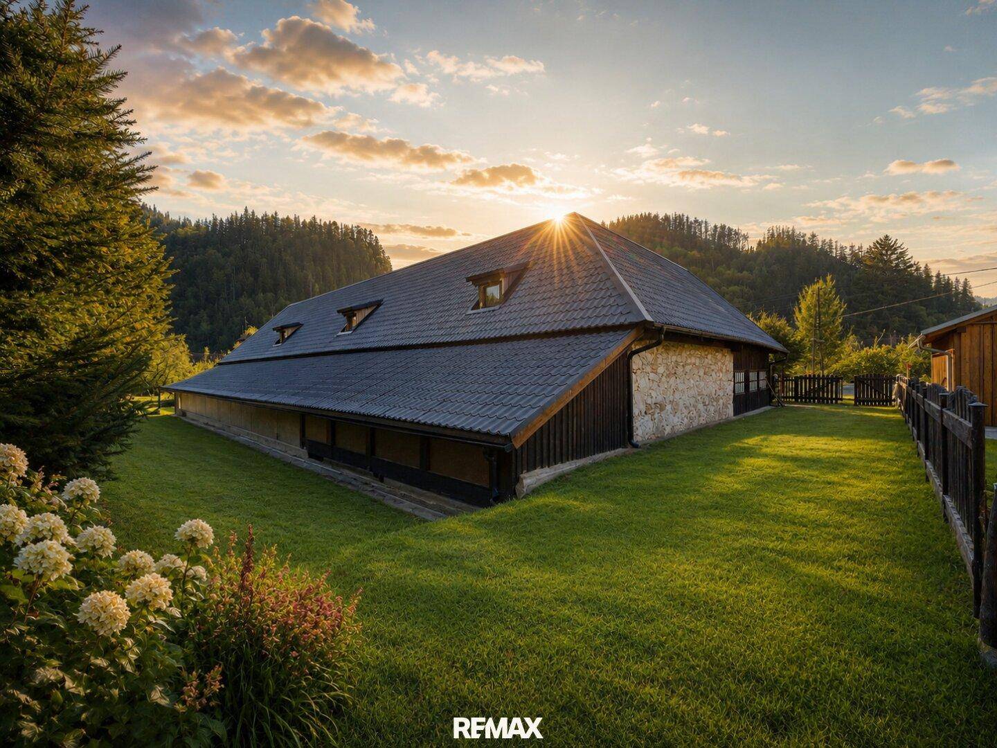 Ländliches Gebäude mit dunklem Ziegeldach und Steinfassade bei Sonnenuntergang.