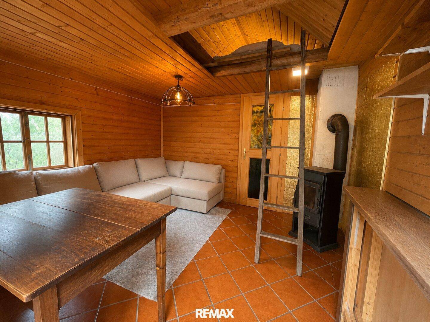 Gemütliches Wohnzimmer mit Holzvertäfelung, Kaminofen und rustikalem Charme.
