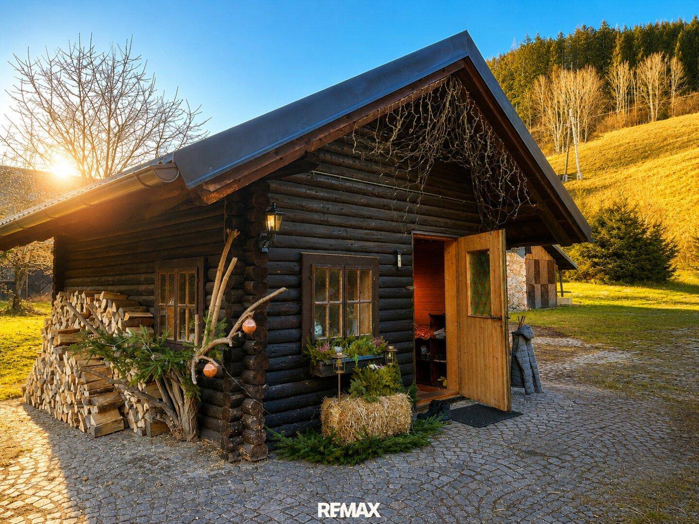 Gemütliche Blockhütte mit Holzstapel und rustikaler Dekoration unter strahlendem Sonnenschein.