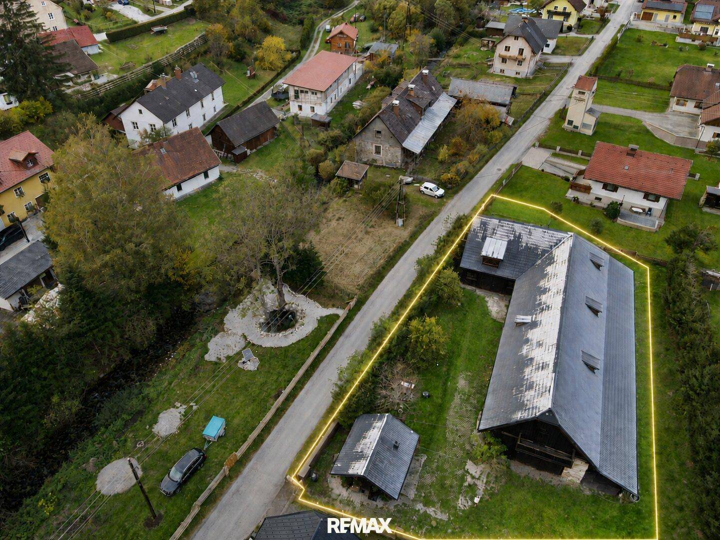 Luftaufnahme des Anwesens mit mehreren Gebäuden, umgeben von grüner Landschaft und Straße.