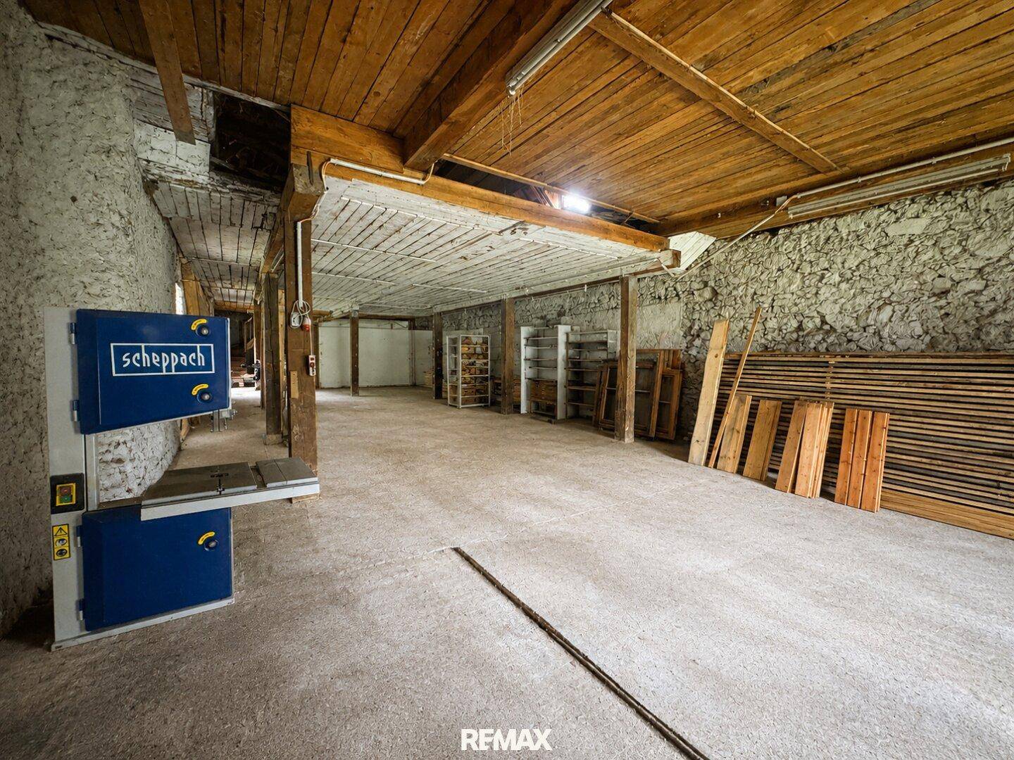 Geräumiger Werkstattraum mit Holzbearbeitungsmaschinen, Holzbalkendecke und Betonboden.