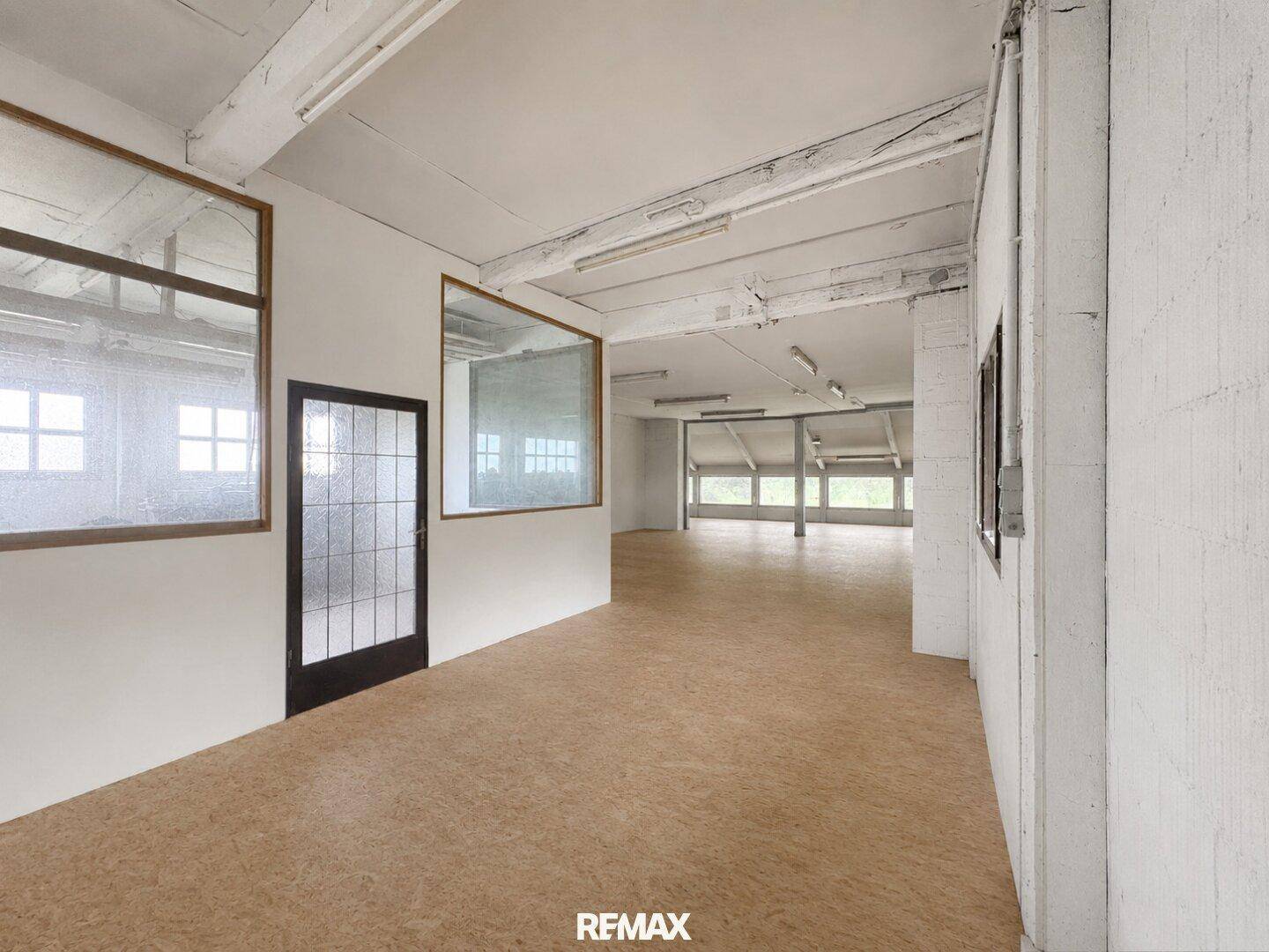 Geräumiger, heller Raum mit Holzbalken und Fenstern, ideal für gewerbliche oder private Nutzung.