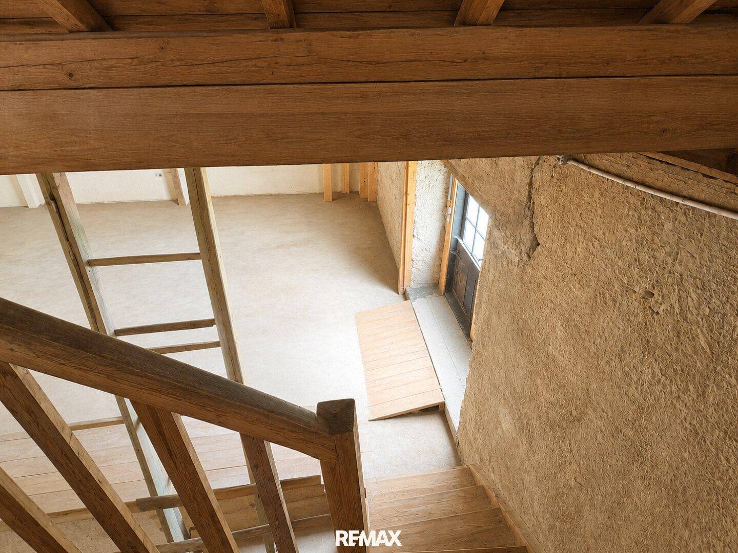 Rustikale Holztreppe führt in einen unteren Bereich mit rauen Wänden und natürlichem Licht.
