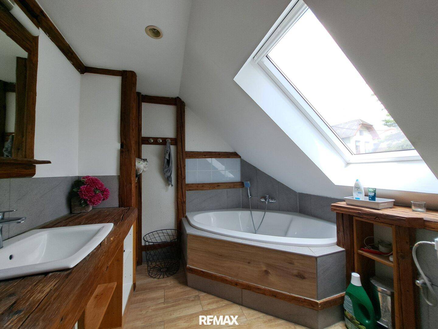 Badezimmer im Dachgeschoss mit Badewanne, Dachfenster und rustikalen Holzdetails.