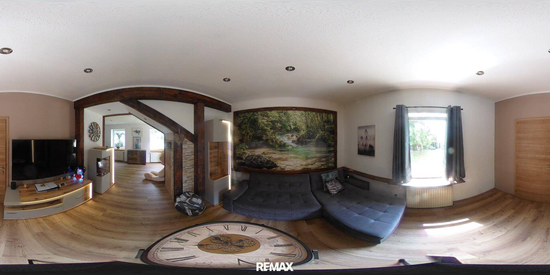 Geräumiges Wohnzimmer mit großem Sofa, Holzbalken und einem großen Wandbild.