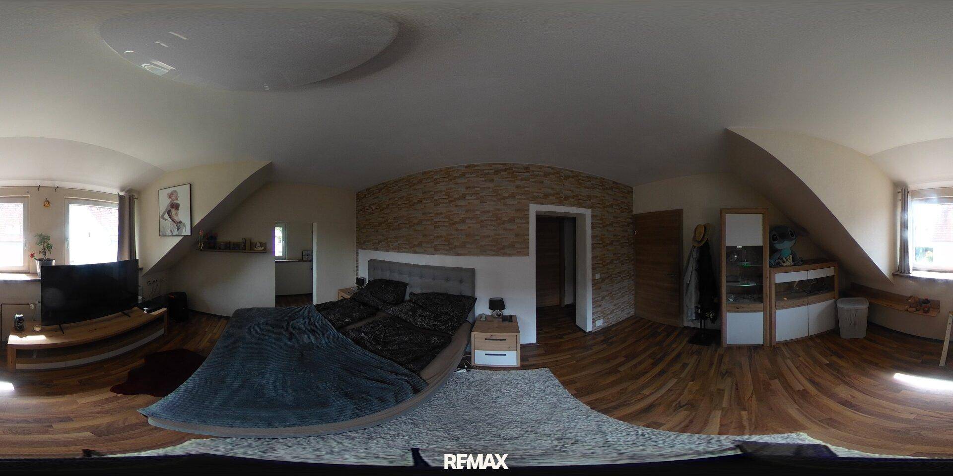 Helles Schlafzimmer mit Doppelbett, gemusterter Akzentwand und Dachschrägen.