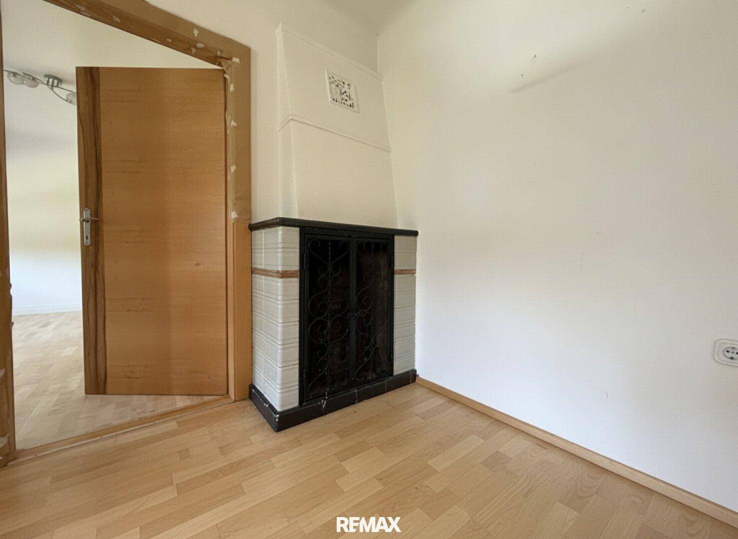 Gemütliches Zimmer mit Parkettboden und einem traditionellen Kachelofen.
