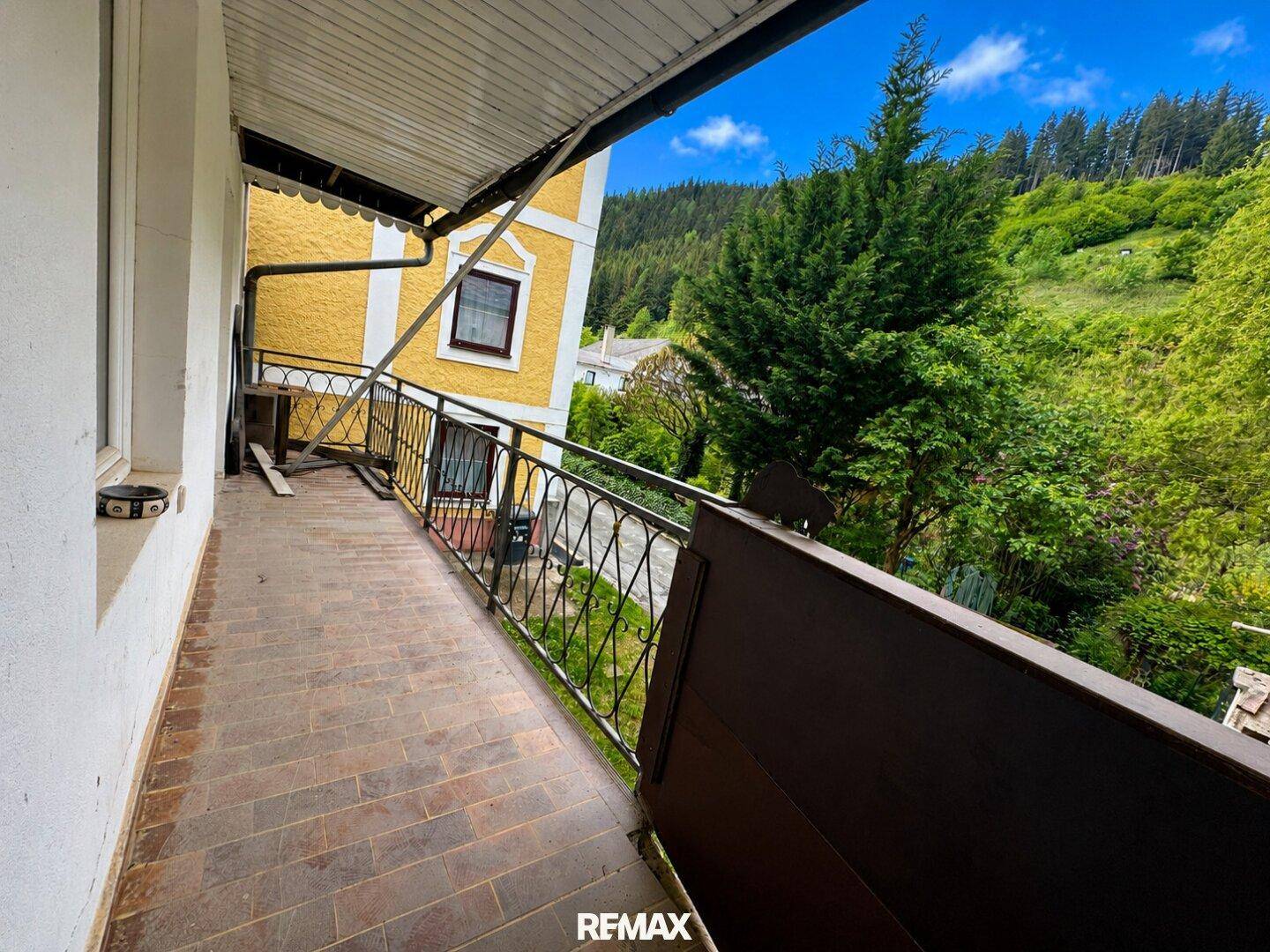 Langer Balkon mit Metallgeländer und Blick auf die bewaldete Hügellandschaft.