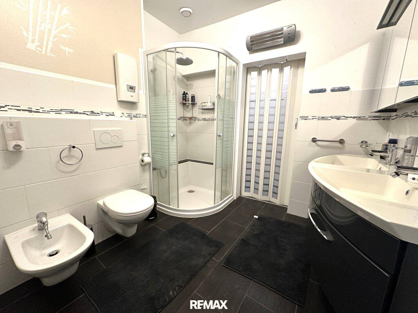 Modernes Badezimmer mit Eckdusche, Toilette, Bidet und einem einzelnen Waschbecken.