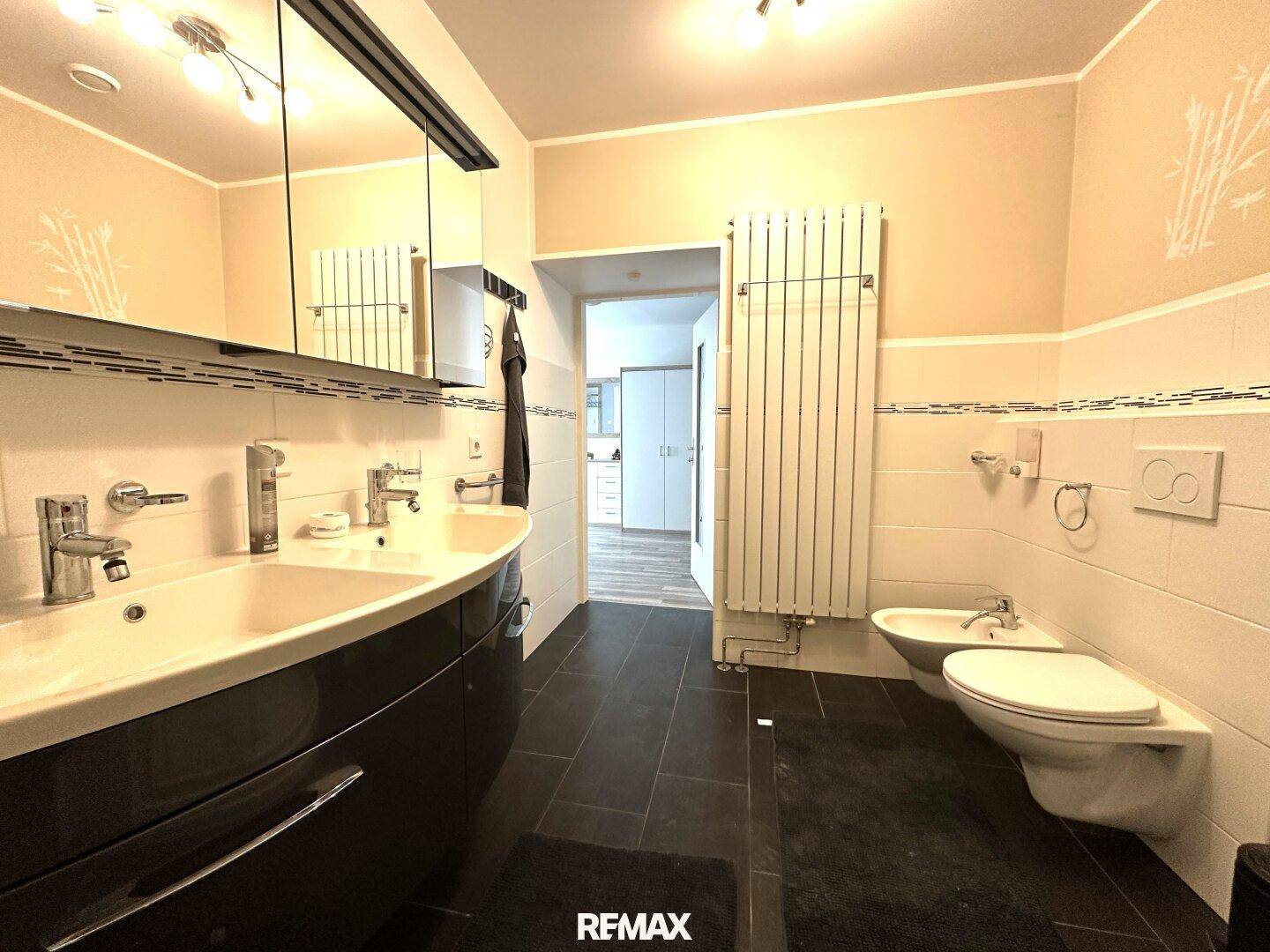 Badezimmer mit Doppelwaschbecken, Bidet, Toilette und beheiztem Handtuchhalter.
