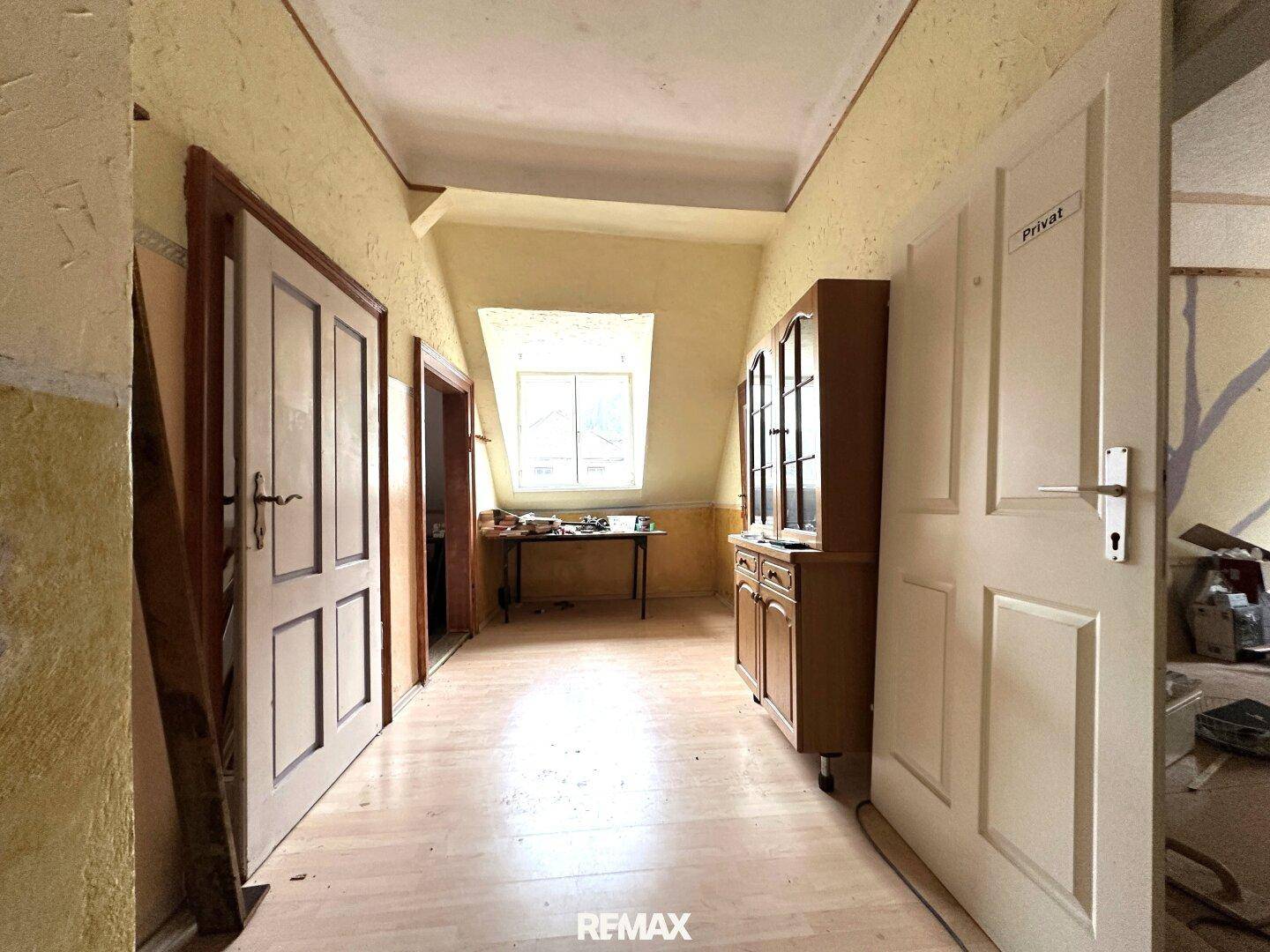 Flur im Dachgeschoss mit schrägen Decken, Holzboden und mehreren Türen.