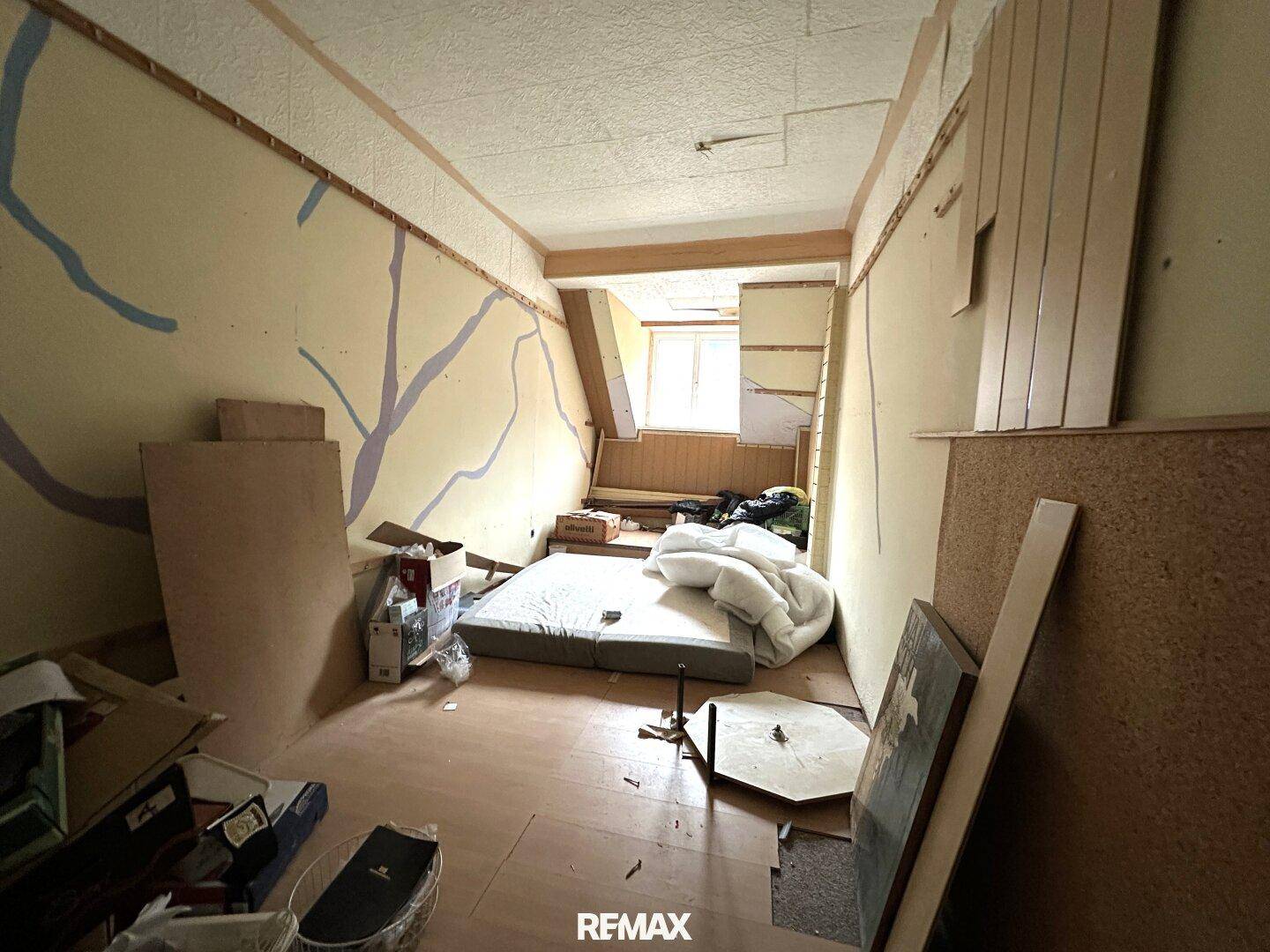 Renovierungsbedürftiges Zimmer mit freigelegten Wänden und Baumaterialien.