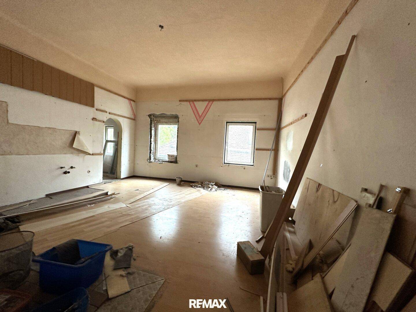 Großes Zimmer in Renovierung mit Holzboden und sichtbaren Spuren der Bauarbeiten.