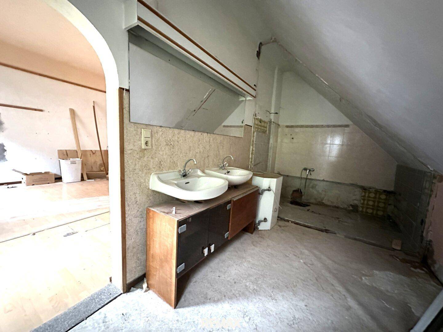 Unfertiges Badezimmer im Dachgeschoss mit Doppelwaschbecken und schrägen Wänden.
