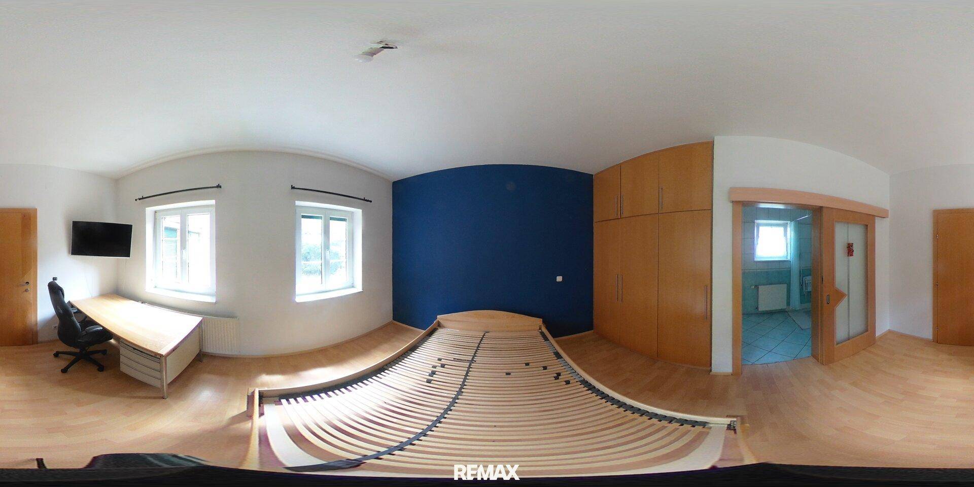 Helles Schlafzimmer mit blauer Akzentwand, Holzbettrahmen und Schiebetür.