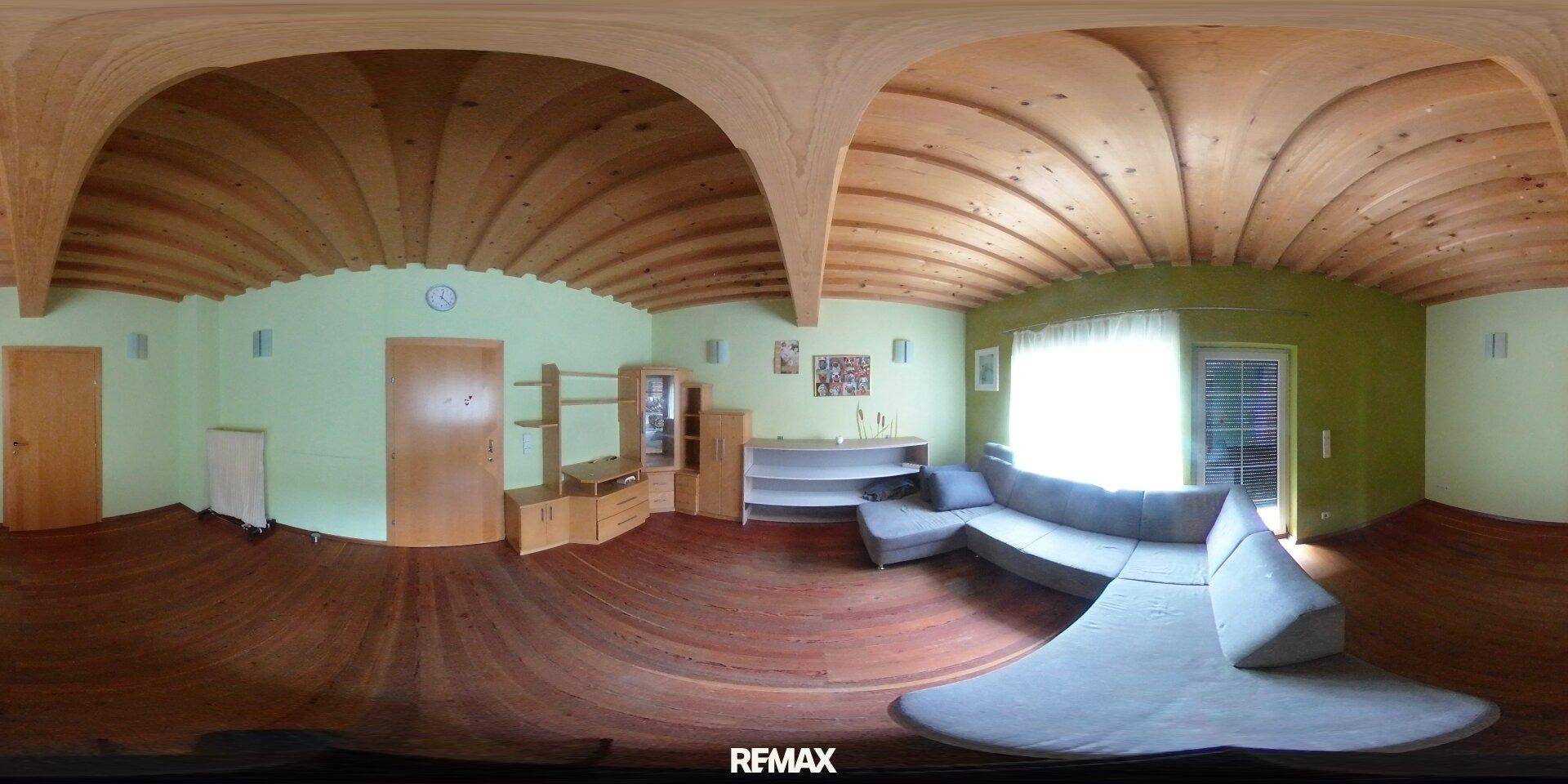Wohnzimmer mit gewölbter Holzdecke, grün gestrichenen Wänden und Sofa.