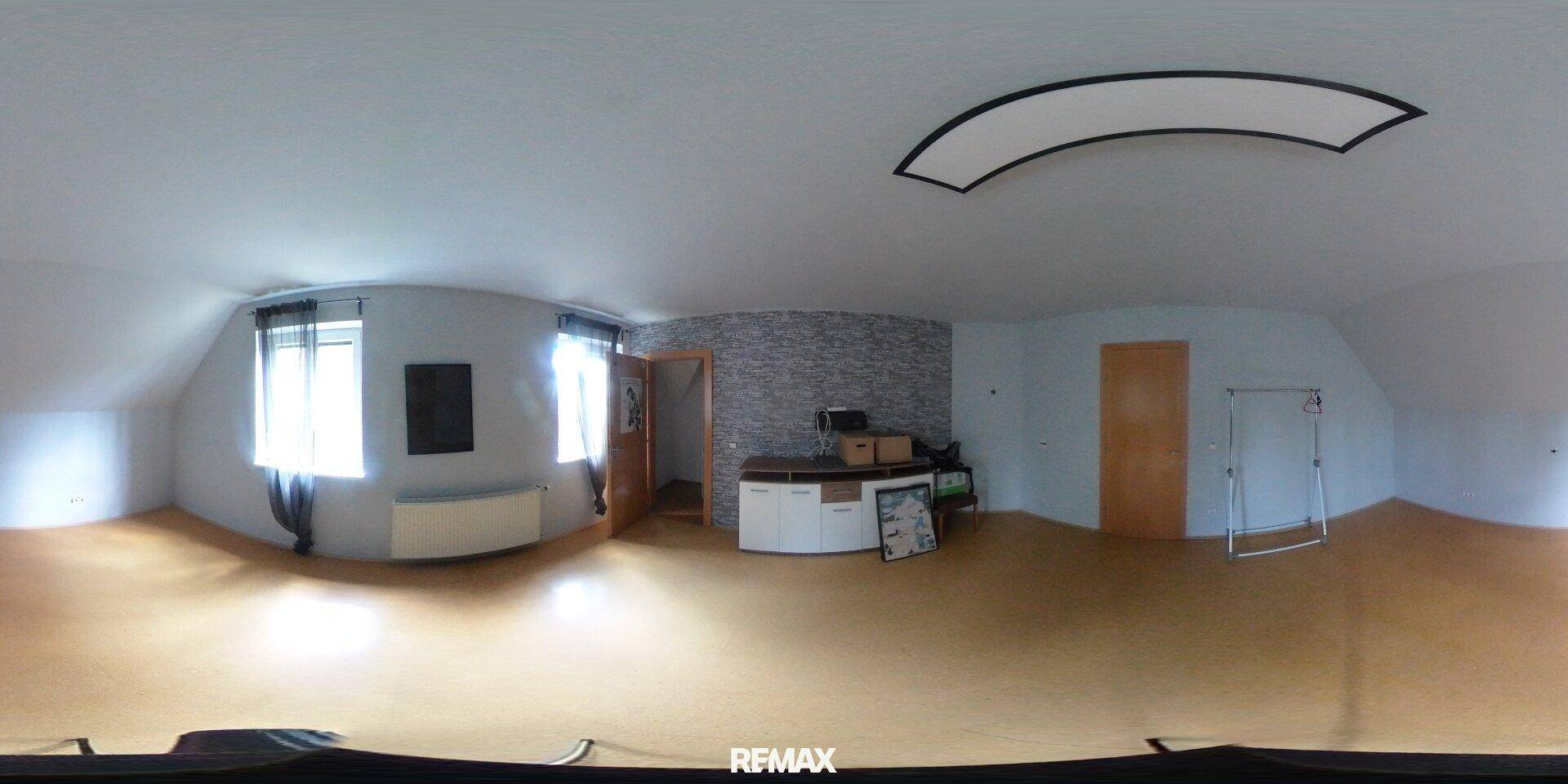 Geräumiges Zimmer im Dachgeschoss mit schrägen Wänden und Steinwandakzent.
