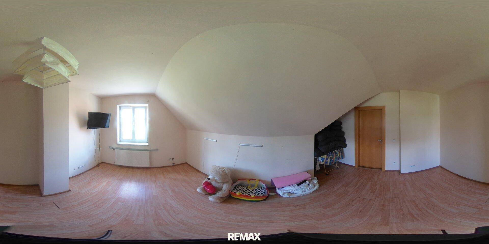 Geräumiges Zimmer im Dachgeschoss mit Laminatboden und schrägen Wänden.