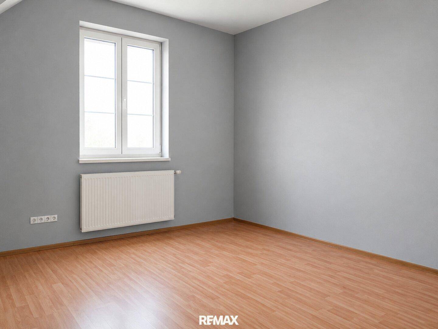 Einfaches Schlafzimmer mit grauen Wänden, Laminatboden und großem Fenster.