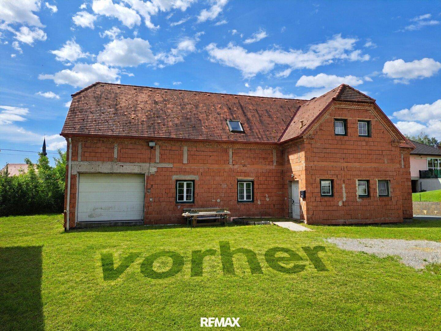Backsteinhaus mit großem Rasenbereich und Garagentor unter blauem Himmel.