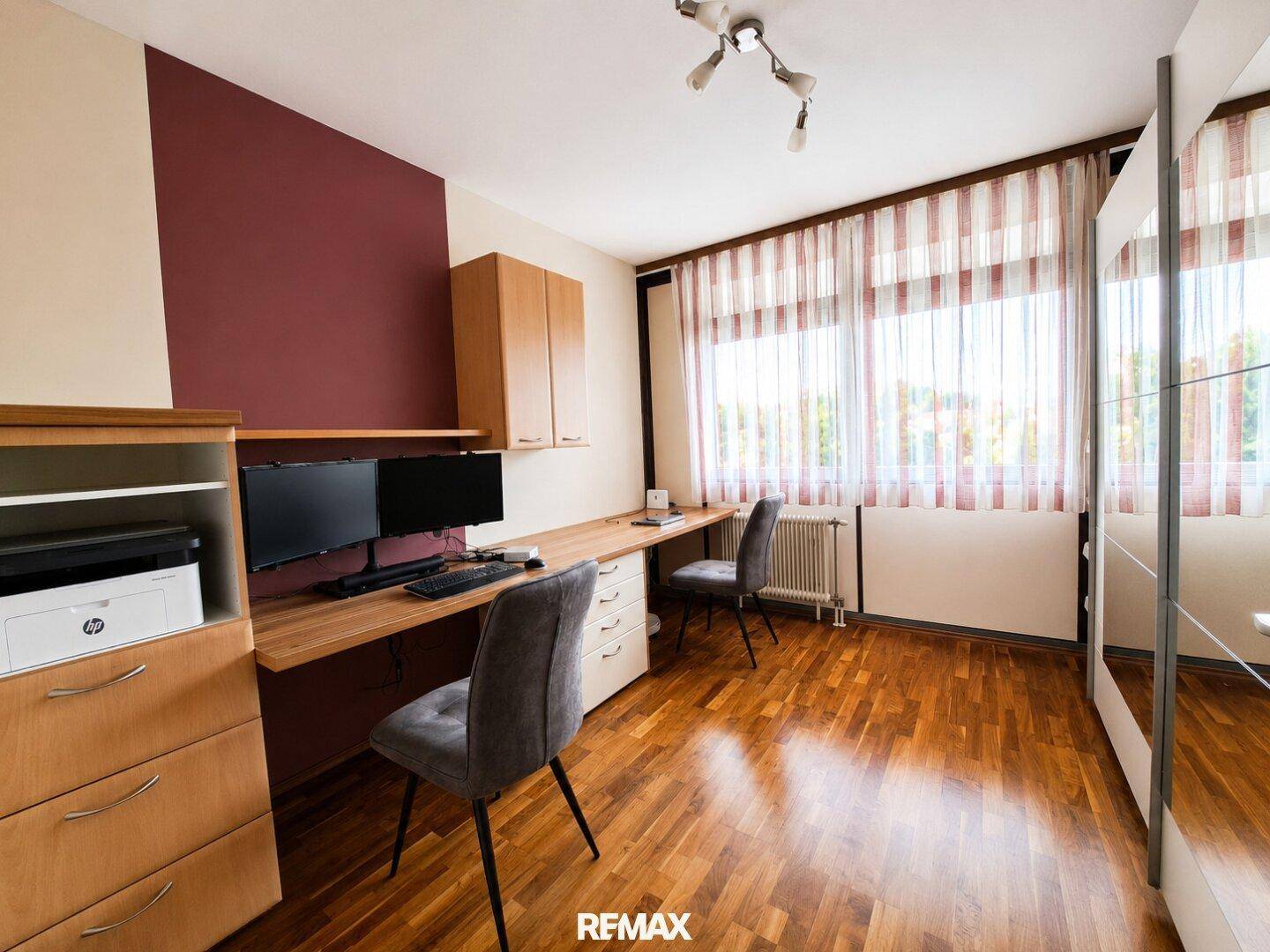 Helles Arbeitszimmer mit Holzparkett, großem Schreibtisch und Stauraum, ideal für Home-Office.