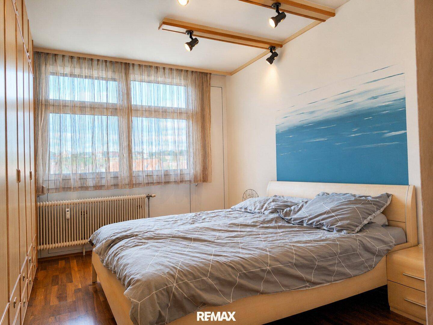 Gemütliches Schlafzimmer mit Doppelbett, Holzparkett und einem modernen Wandgemälde.