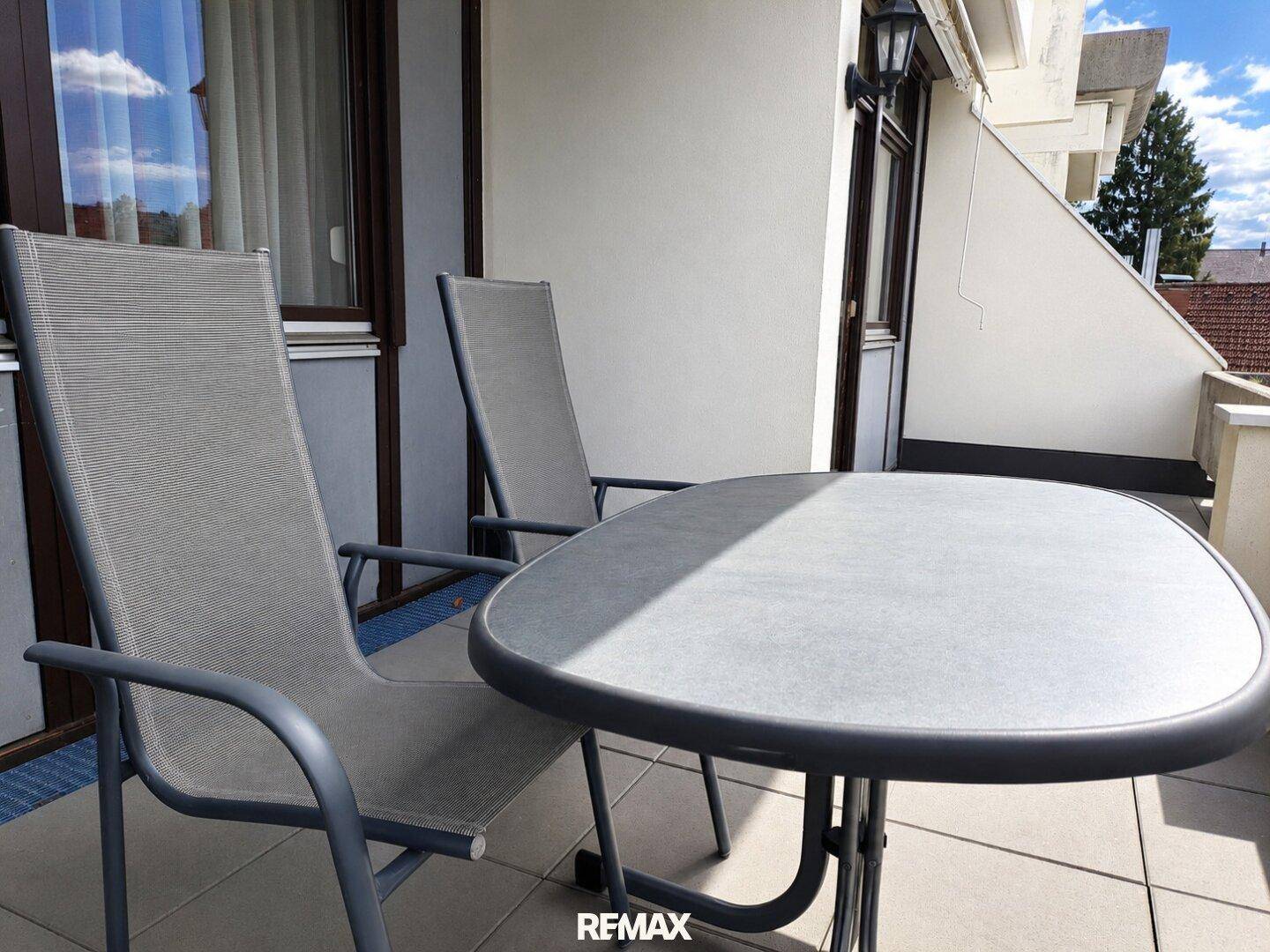 Gemütlicher Balkon mit Tisch und Stühlen, ideal für entspannte Stunden im Freien.