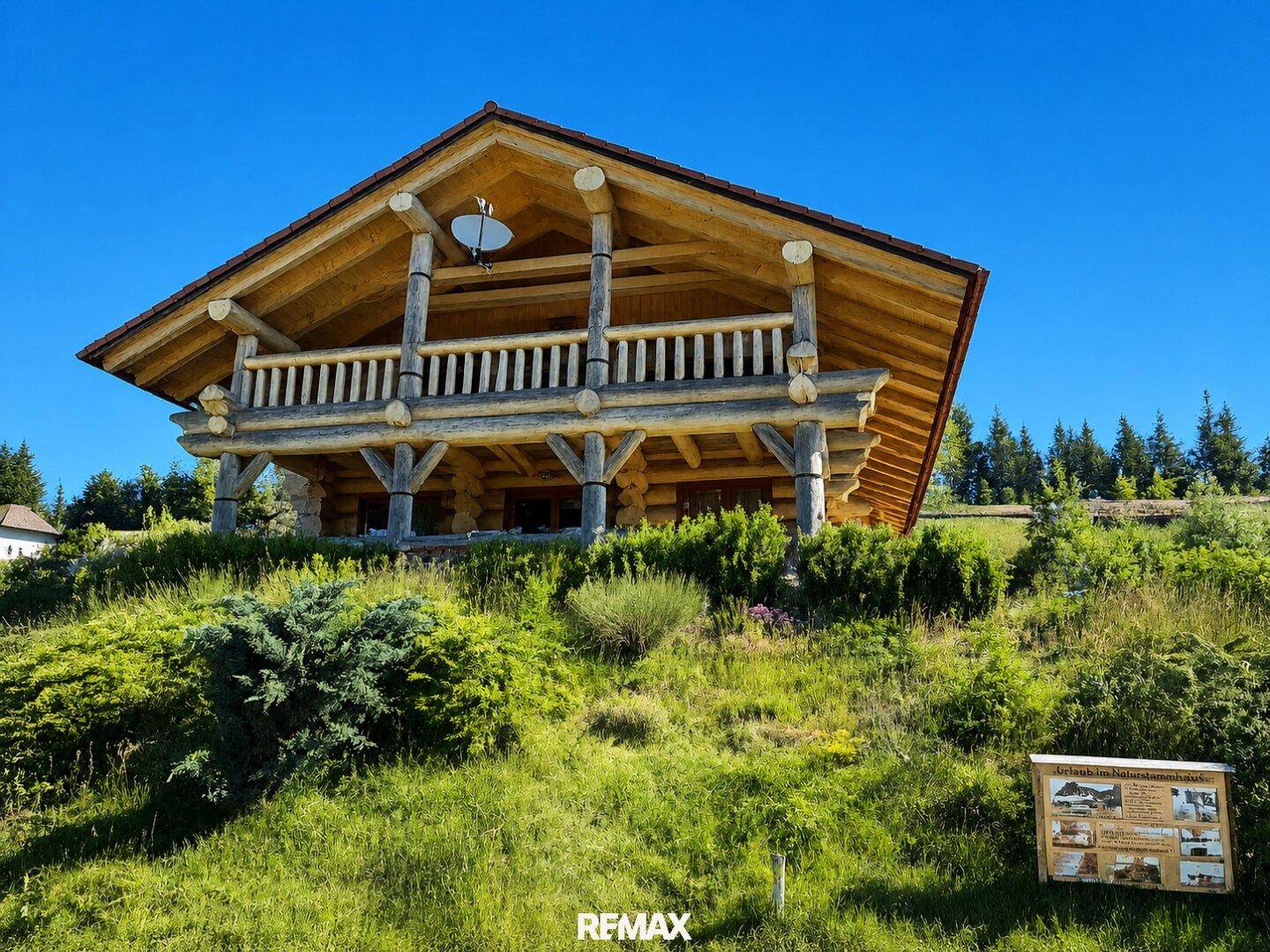 Rustikales Blockhaus in alpiner Landschaft mit weitem Blick und sonnigem Wetter.