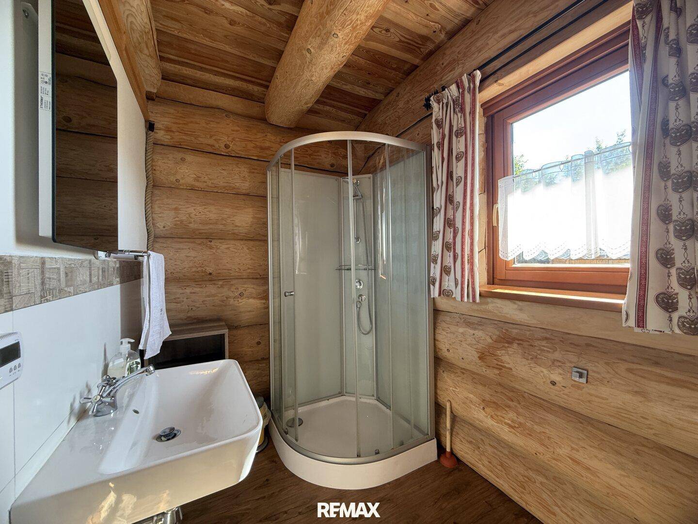 Kleines Badezimmer mit Duschkabine, Waschbecken und Holzvertäfelung im Landhausstil.