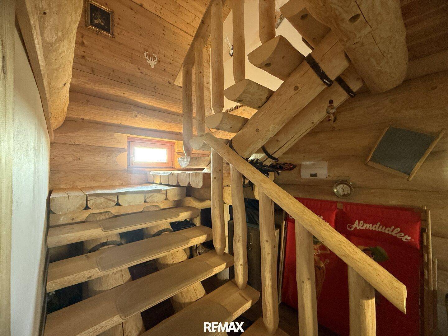 Rustikale Holztreppe mit Geländer, die die verschiedenen Ebenen des Blockhauses verbindet.