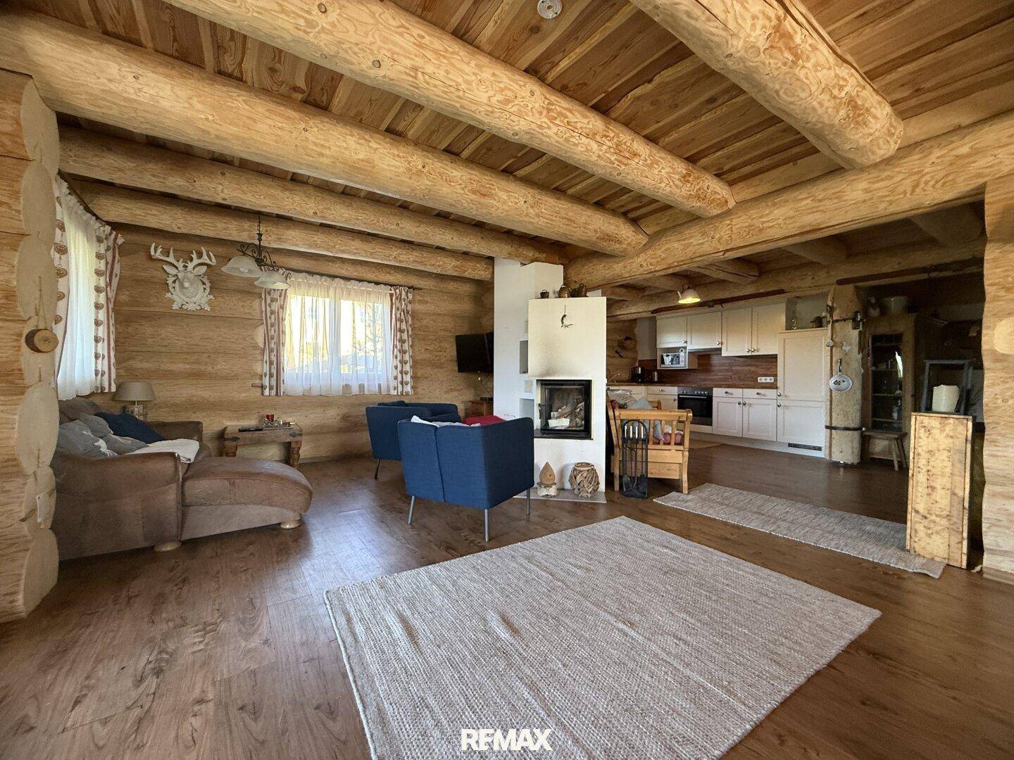 Geräumiger Wohnbereich mit Kamin, bequemen Sofas und offener Küche in einem Holzhaus.
