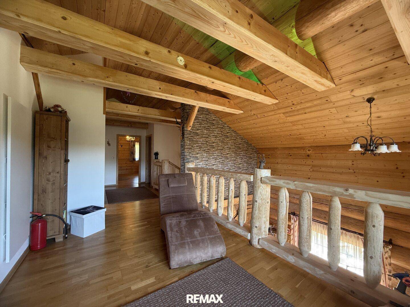 Offener Galeriebereich im Obergeschoss mit Liege und Blick auf die Holzkonstruktion.