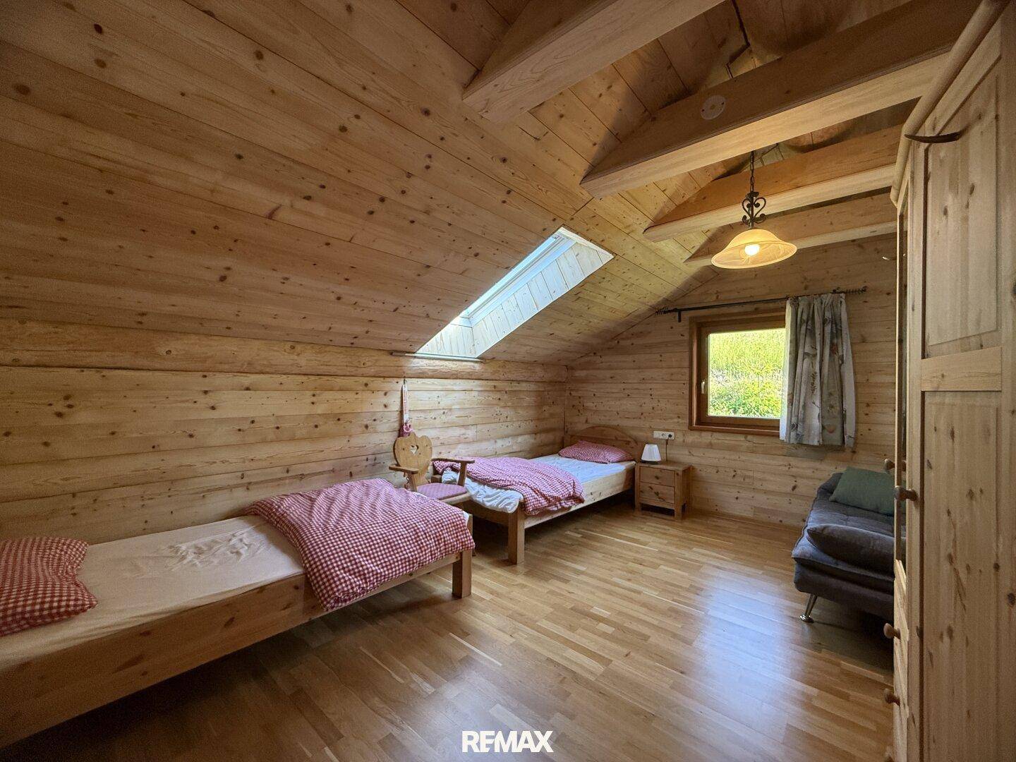 Gemütliches Schlafzimmer im Dachgeschoss mit zwei Einzelbetten, Holzvertäfelung und Dachfenster.