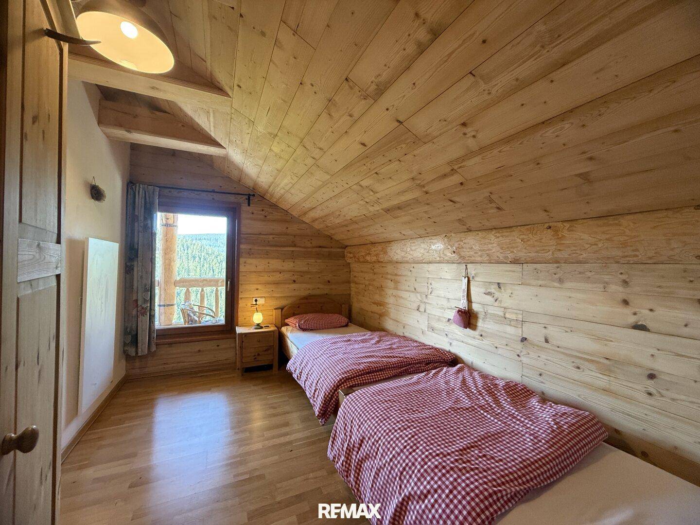 Schlafzimmer mit zwei Einzelbetten, Holzvertäfelung und direktem Zugang zum Balkon.