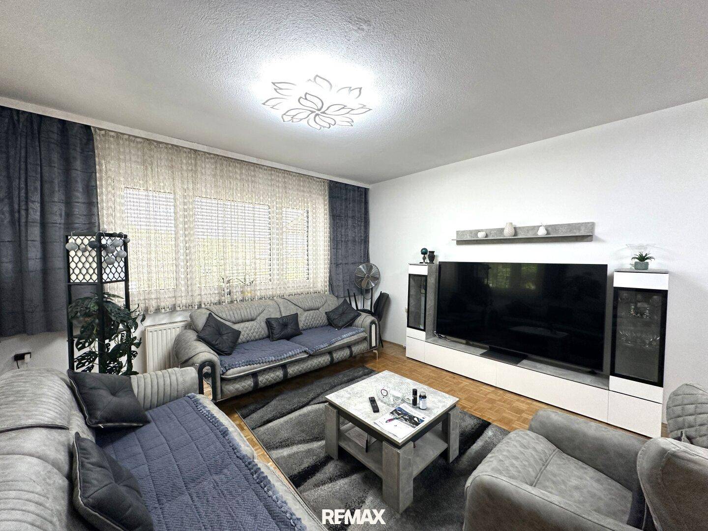 Gemütliches Wohnzimmer mit modernen Sofas, Teppich und einem großen Fernseher.