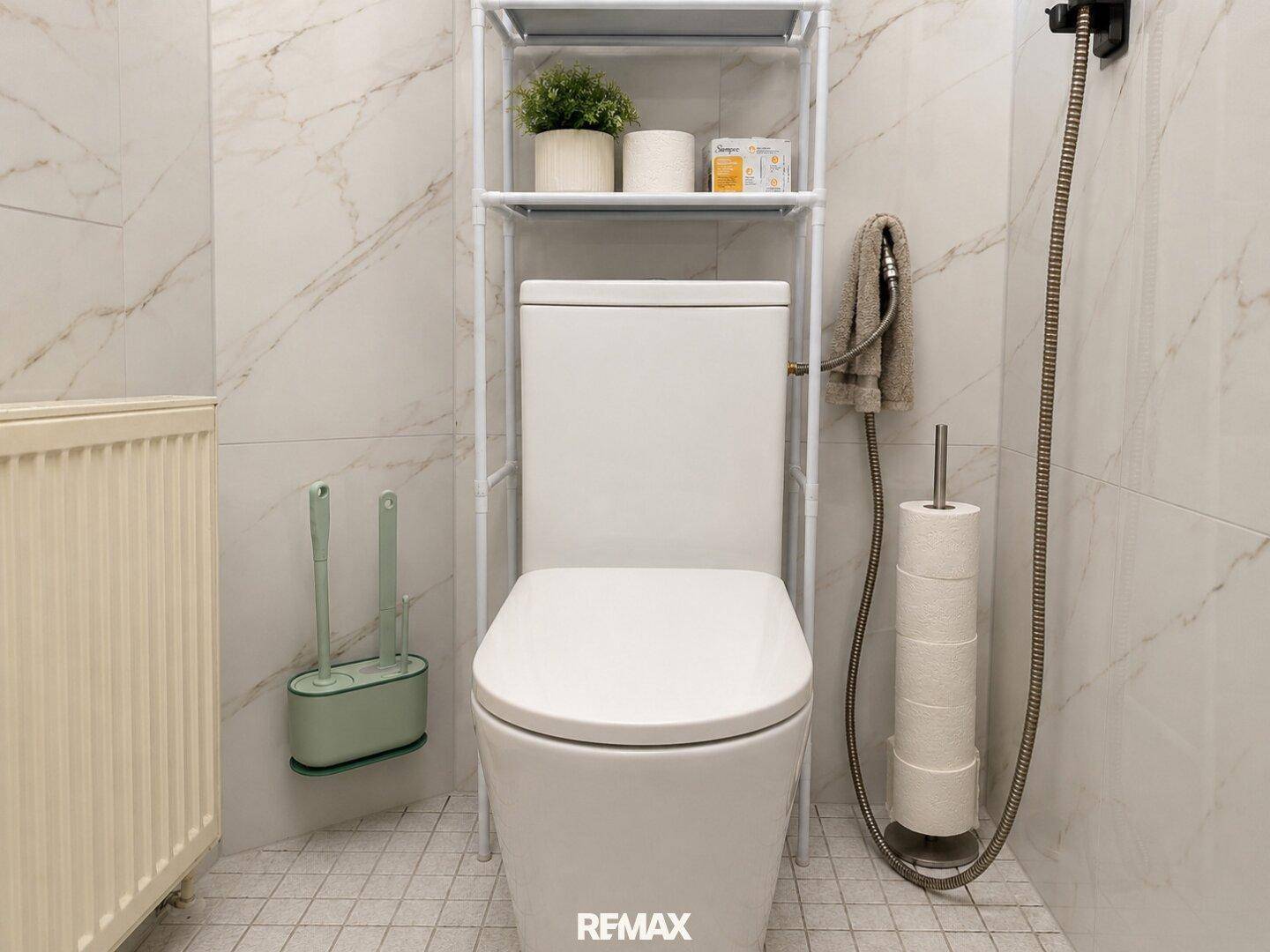 Kleines WC mit modernen Fliesen, Toilette und praktischem Regal über dem Spülkasten.